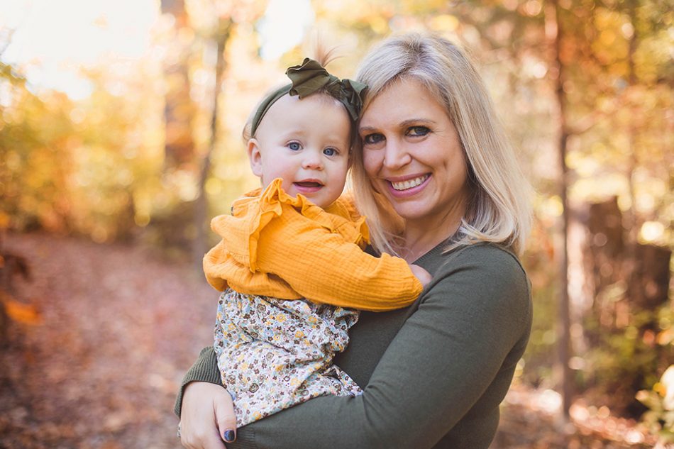 mom and baby girl posing in the fall leaves