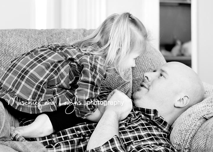 Little girl and her daddy snuggle on the couch