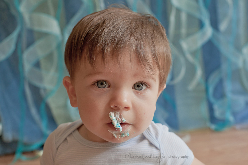 messy baby eating cake during first birthday pictures