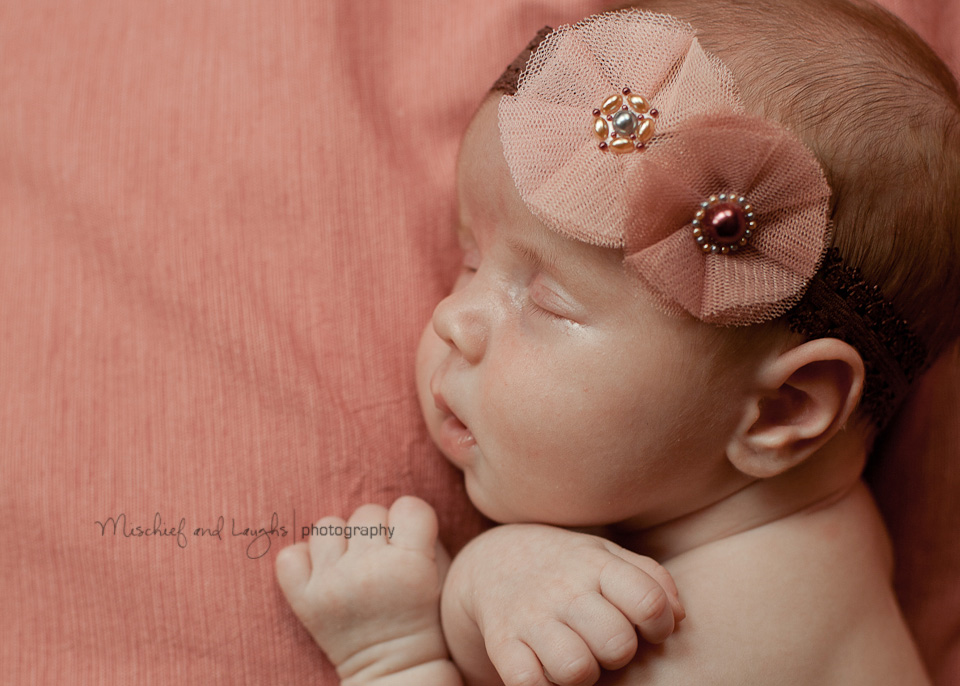 tired newborn baby with pink hair bow
