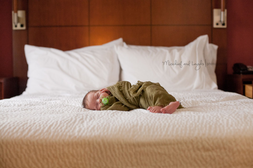 baby with binky laying on a bed lifestyle pictures