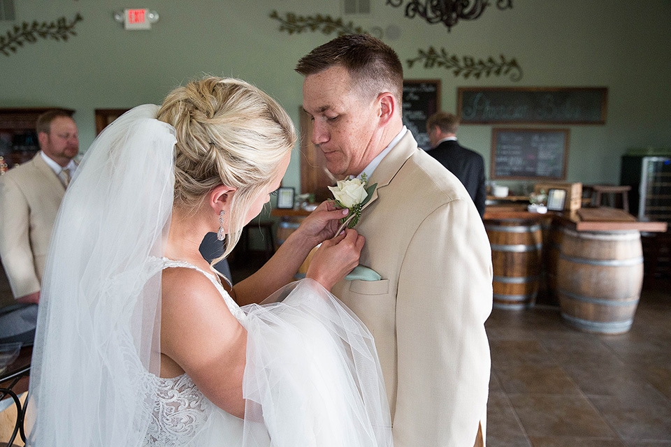 Bride puts boutonniere on groom's tux, Finger Lakes wedding photographer