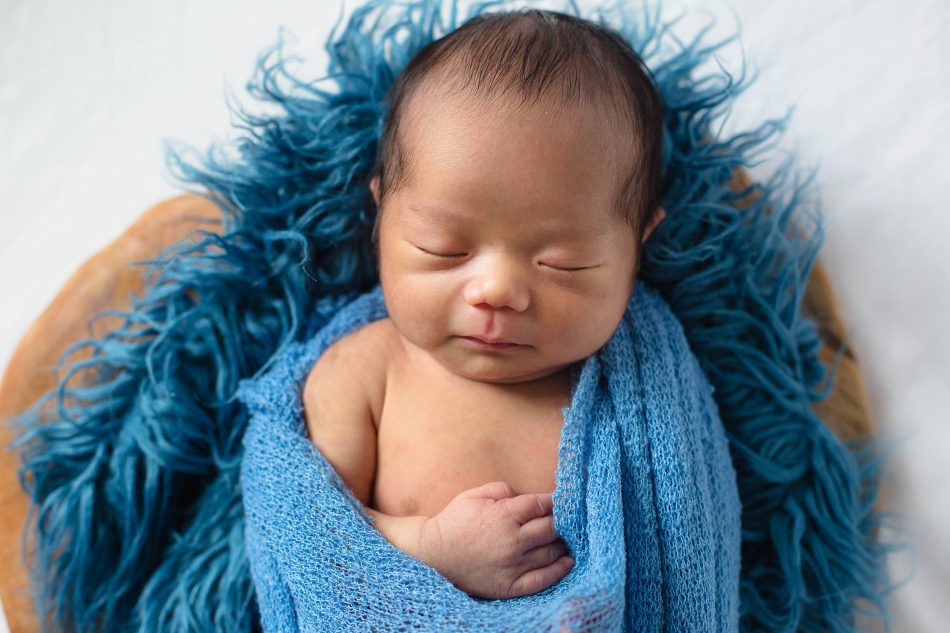 Newborn baby laying on blue fur blanket