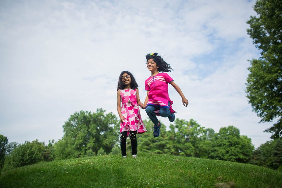 two girls jumping during their family photo session in Blue Ash