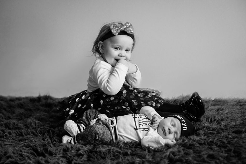 big sister poses with little brother during the newborn photo session