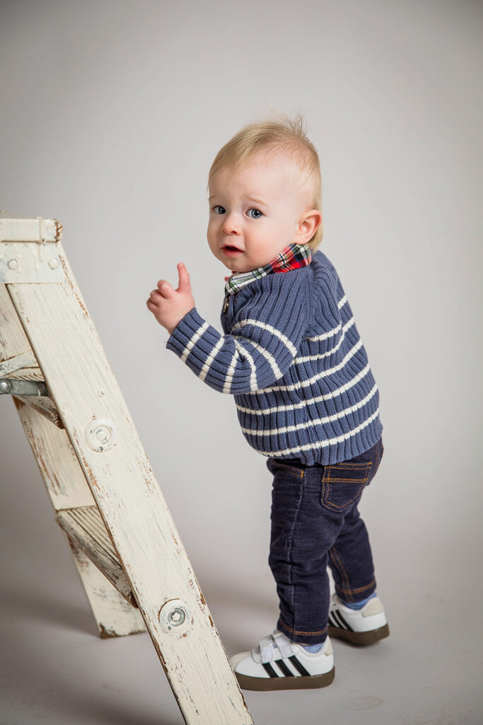 Toddler exploring a photography studio during his first birthday milestone session.