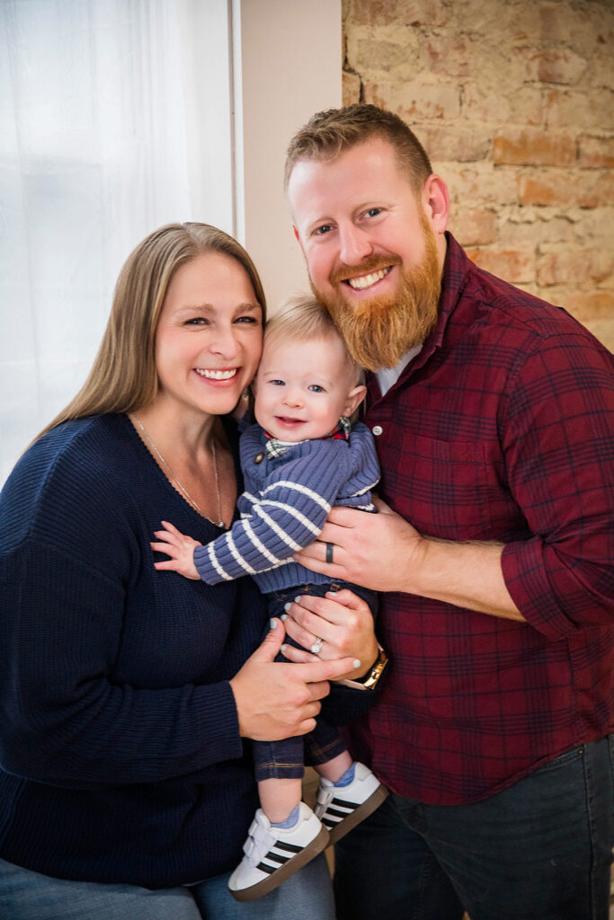 Mom, dad, and their one-year-old son sharing a sweet moment during his birthday photoshoot.