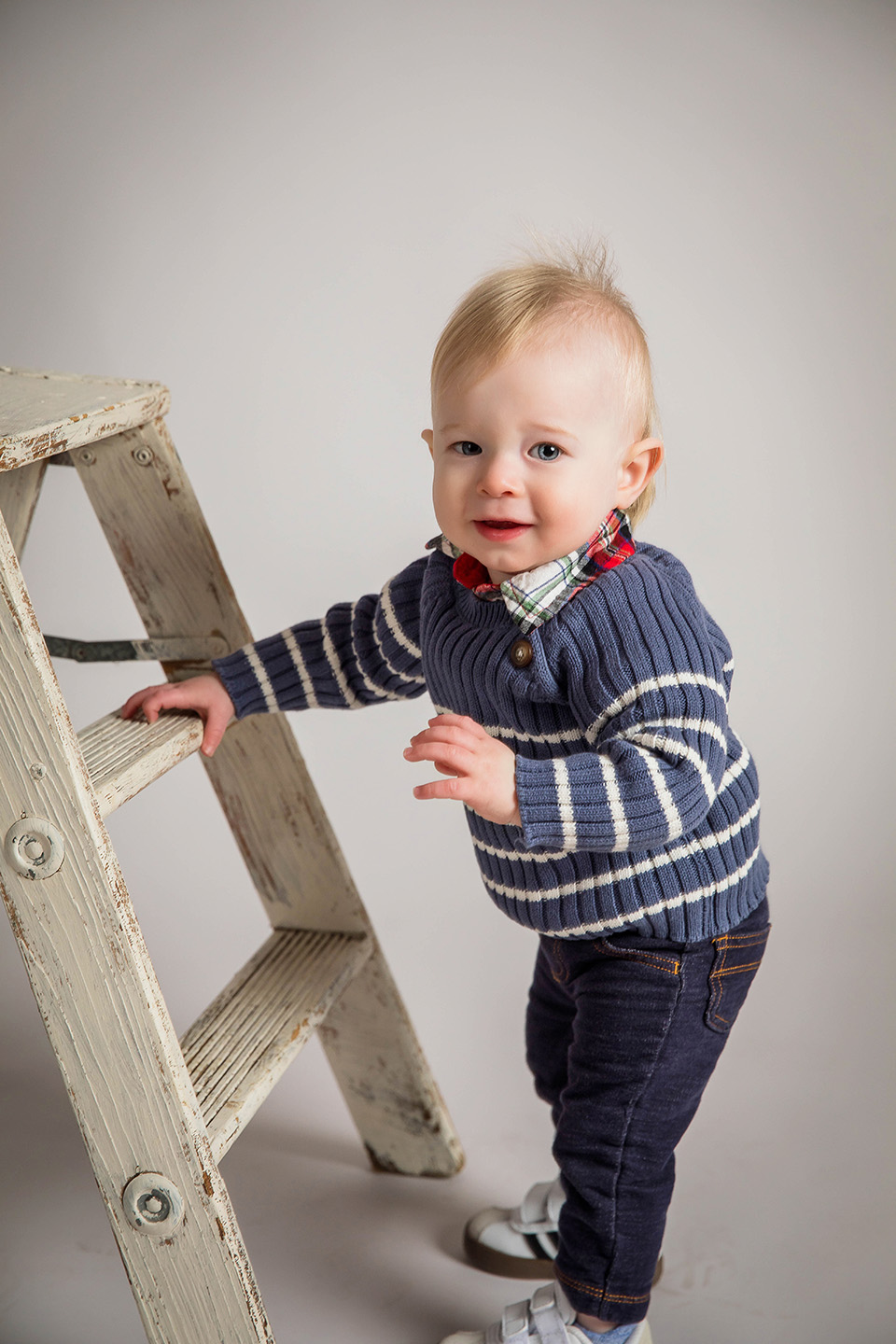 One-year-old boy smiling during his first birthday photo session in a Sharonville, OH studio.