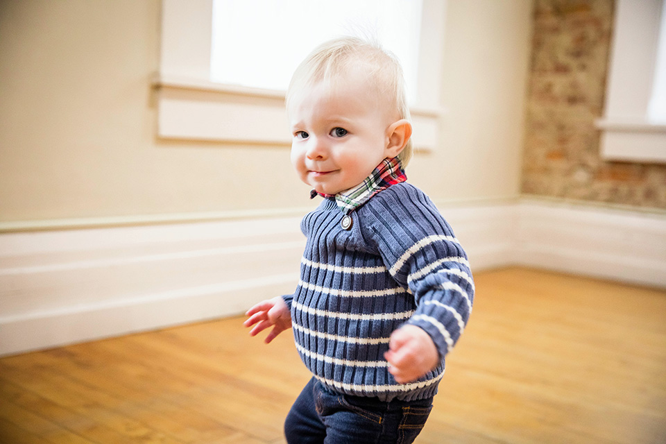 One-year-old boy laughing while exploring the studio during his birthday photoshoot.