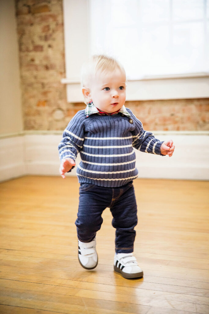 Happy toddler taking steps in a milestone photography session at a Sharonville studio.