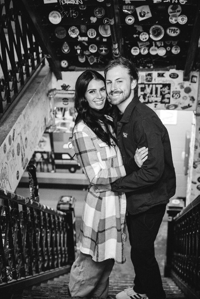 Couple posing by large windows inside the brewery for authentic Cincinnati engagement photos