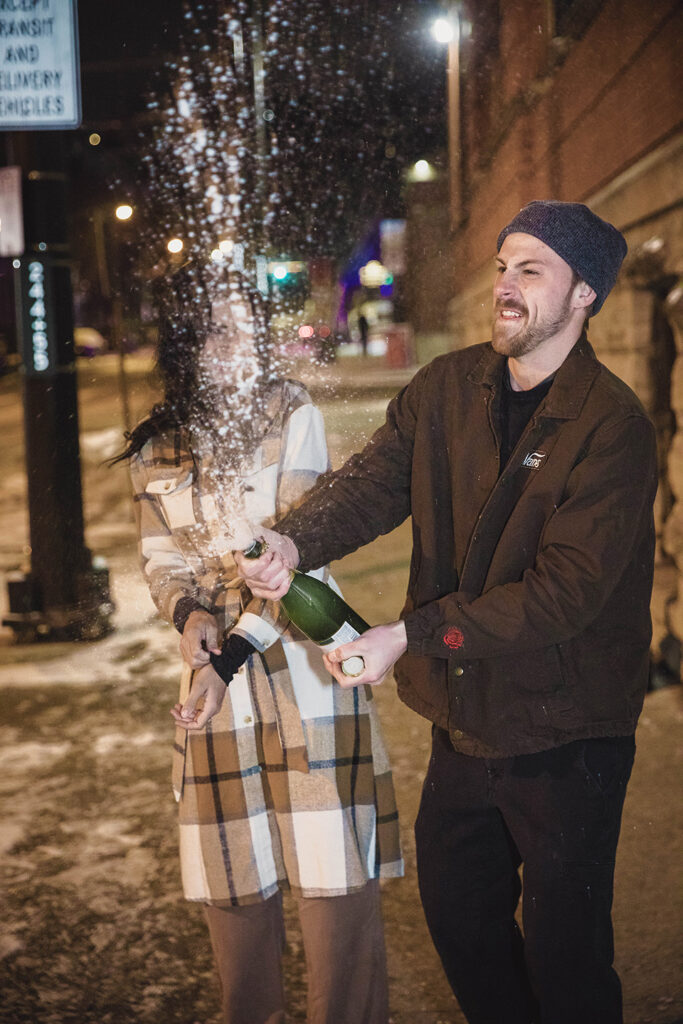 Cincinnati engagement photo capturing a spontaneous champagne spray moment in winter.