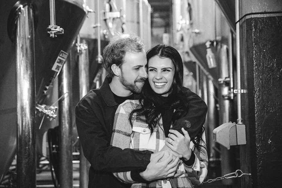 Winter engagement photo featuring a smiling couple indoors at Rhinegeist Brewery