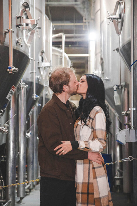 Couple sharing a loving embrace inside Rhinegeist Brewery during their surprise engagement session