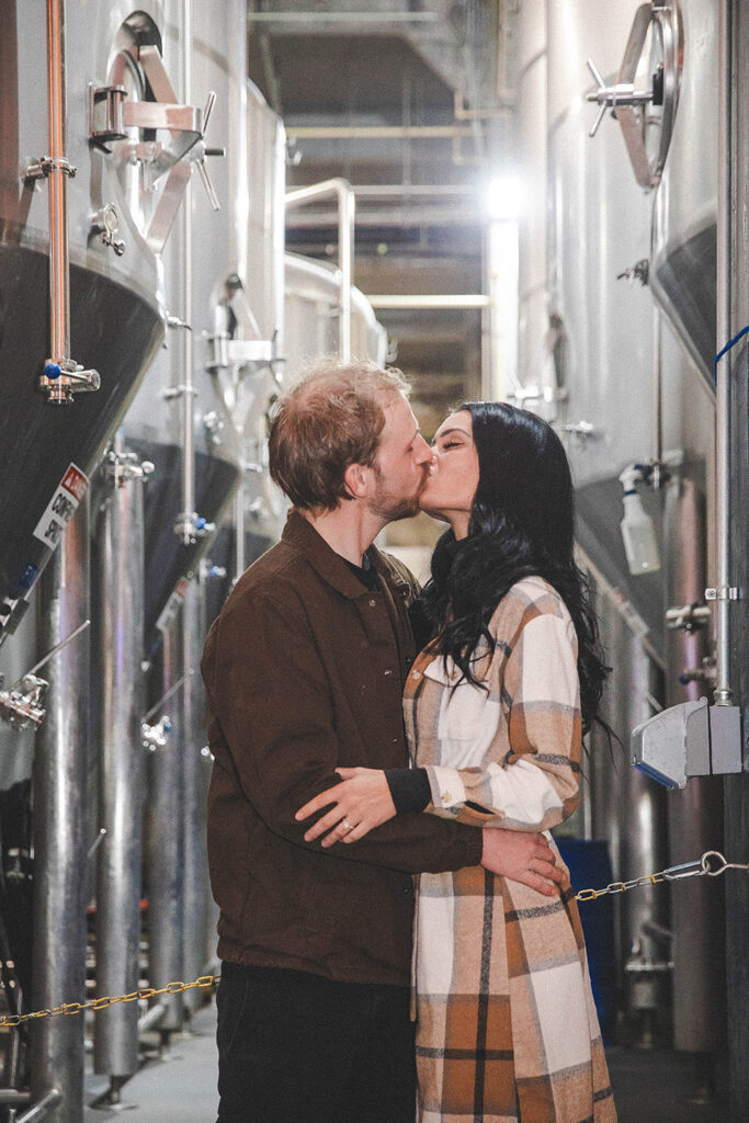 Couple sharing a loving embrace inside Rhinegeist Brewery during their surprise engagement session