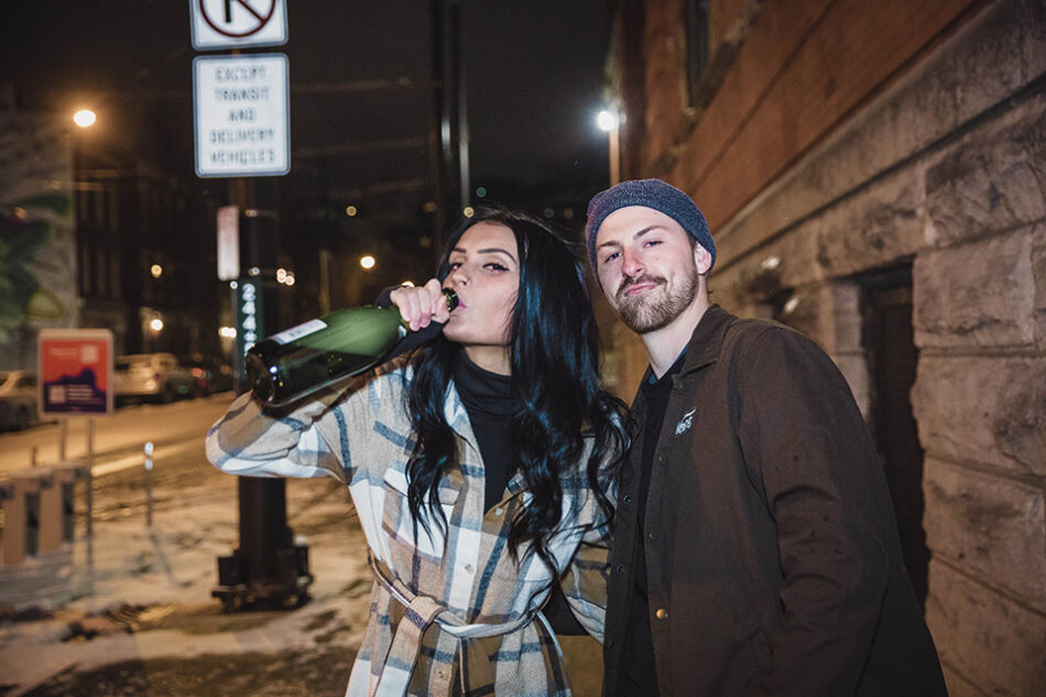 Couple sharing a tender kiss outdoors during a snowy, cold engagement session.