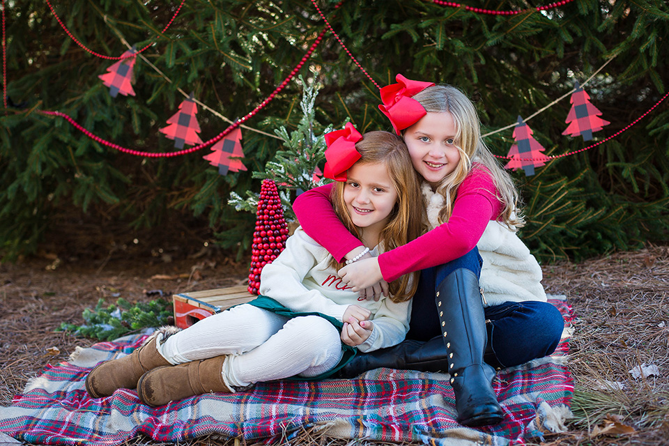 Outdoor Christmas photo session, mini sessions in Cincinnati, siblings sitting on a blanket with Christmas trees in the background