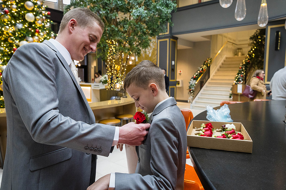 groom putting boutonniere on child