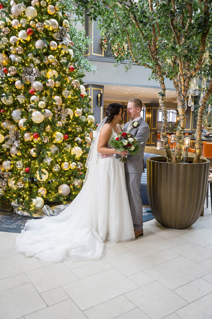 bride and groom at lytle park hotel at Christmastime with decorations and Christmas tree